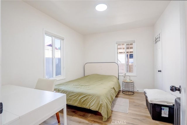 bedroom featuring light wood-type flooring, baseboards, and multiple windows