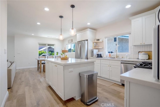 kitchen featuring appliances with stainless steel finishes, light wood finished floors, a sink, and a kitchen island