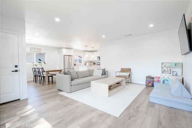 living room featuring recessed lighting, light wood finished floors, visible vents, and baseboards