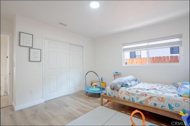 bedroom featuring light wood-style floors, a closet, and visible vents