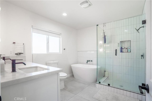 full bath with vanity, tile patterned flooring, toilet, a freestanding bath, and a stall shower