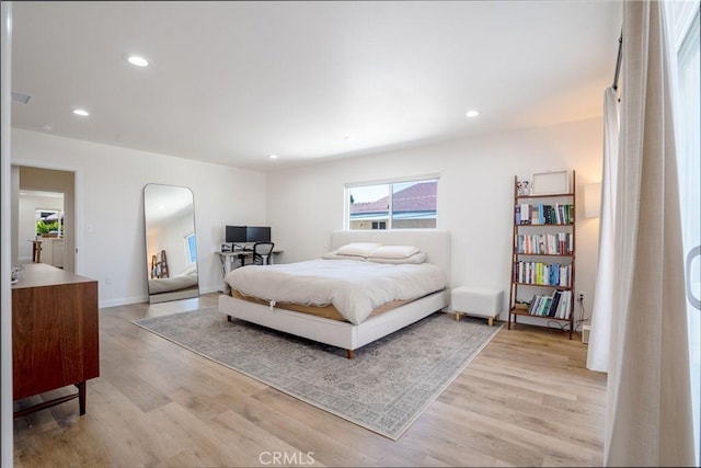 bedroom with recessed lighting, arched walkways, and light wood finished floors