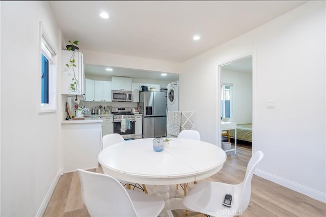 dining space with stacked washer / dryer, recessed lighting, baseboards, and light wood-style flooring