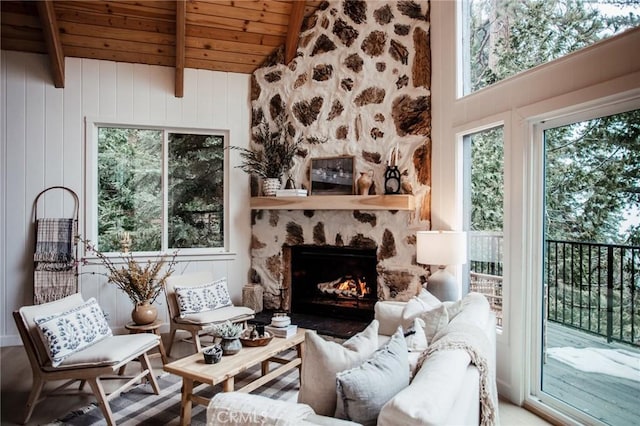 living area featuring wood ceiling, a fireplace, and vaulted ceiling with beams