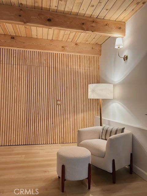 sitting room with beamed ceiling, light wood finished floors, and wooden ceiling