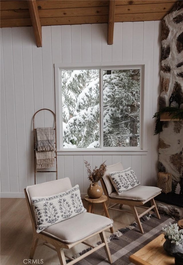 sitting room featuring a decorative wall, wood finished floors, beam ceiling, and wooden ceiling