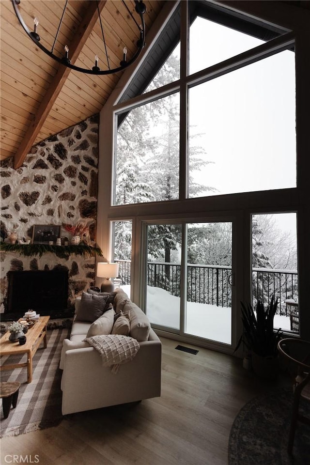 living room featuring visible vents, wooden ceiling, a stone fireplace, wood finished floors, and high vaulted ceiling