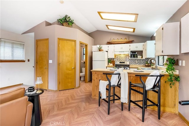 862 Strawberry Peak Rd, Twin Peaks, CA 92391 - kitchen featuring gas stove, freestanding refrigerator, a peninsula, lofted ceiling, and under cabinet range hood