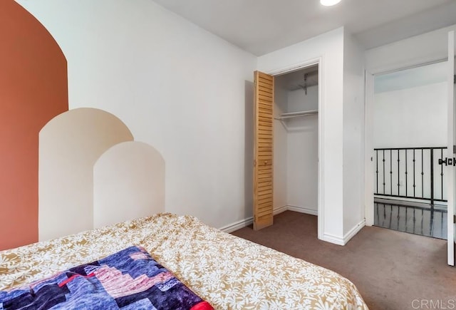carpeted bedroom with arched walkways, a closet, and baseboards