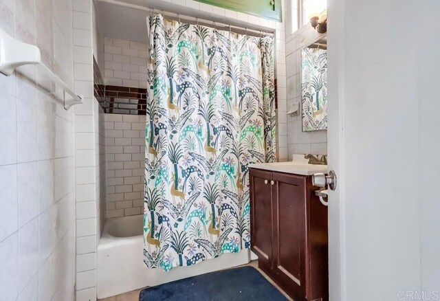 full bath featuring shower / bath combo with shower curtain, tile walls, and vanity