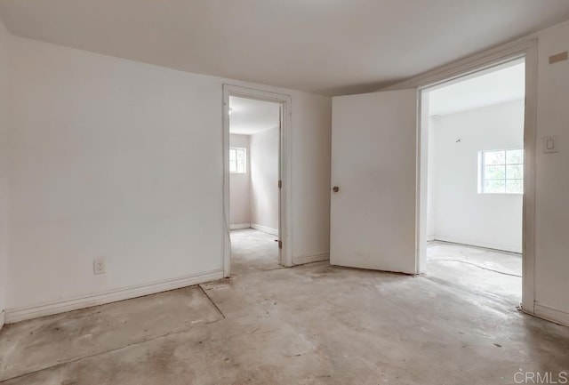 unfurnished room with concrete floors and baseboards