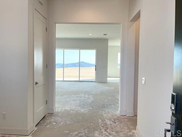 hall featuring baseboards and unfinished concrete flooring