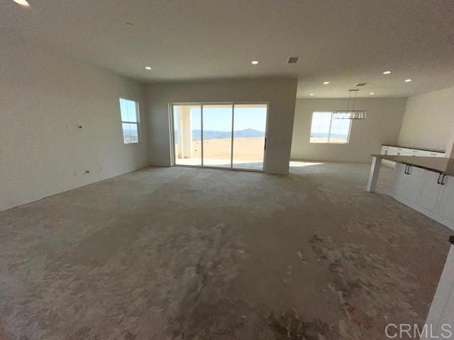unfurnished living room featuring recessed lighting, a wealth of natural light, visible vents, and carpet floors