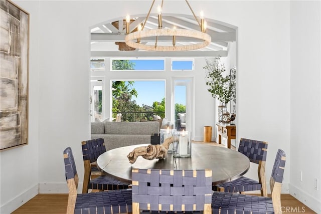 dining area featuring an inviting chandelier, baseboards, wood finished floors, and beamed ceiling