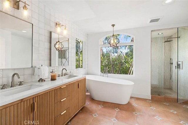 bathroom featuring a sink, a soaking tub, a tile shower, and visible vents
