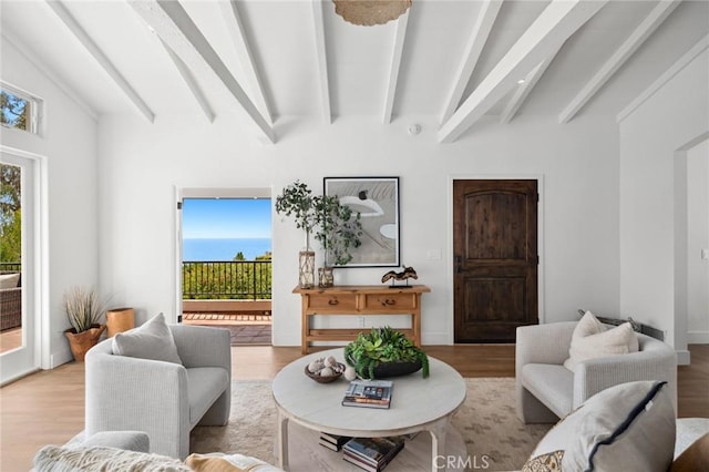 living room with a healthy amount of sunlight, vaulted ceiling with beams, and wood finished floors