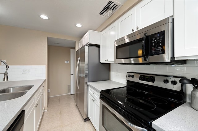 kitchen featuring white cabinets, visible vents, decorative backsplash, stainless steel appliances, and a sink