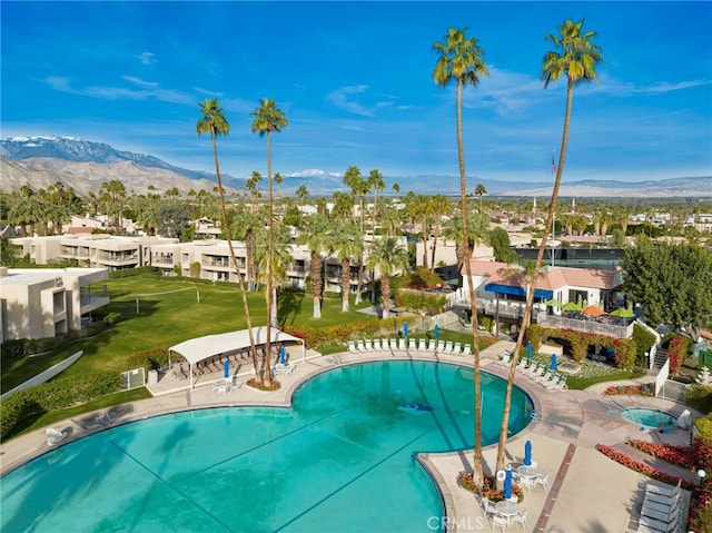 community pool with a patio, a residential view, a yard, and a mountain view