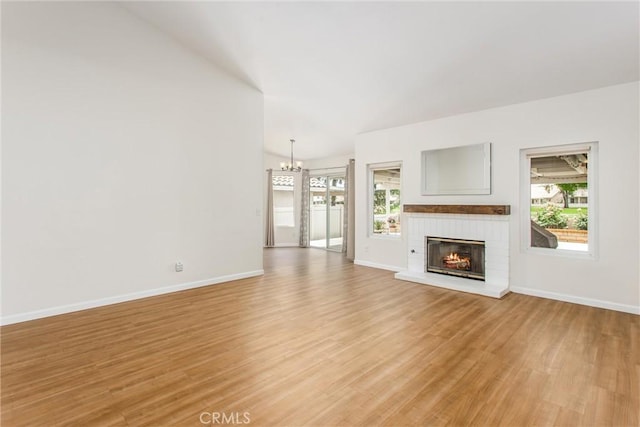 883 Riviera Ave, Banning, CA 92220 - unfurnished living room with a chandelier, light wood-type flooring, a brick fireplace, and baseboards