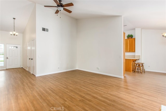 883 Riviera Ave, Banning, CA 92220 - unfurnished living room featuring a chandelier, ceiling fan, light wood finished floors, high vaulted ceiling, and baseboards