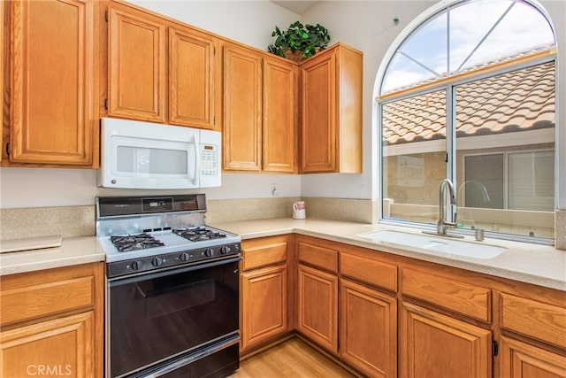 883 Riviera Ave, Banning, CA 92220 - kitchen with white microwave, range with gas stovetop, a sink, and light countertops
