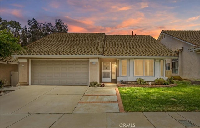 883 Riviera Ave, Banning, CA 92220 - view of front of home featuring concrete driveway, a garage, a front yard, stucco siding, and a tiled roof