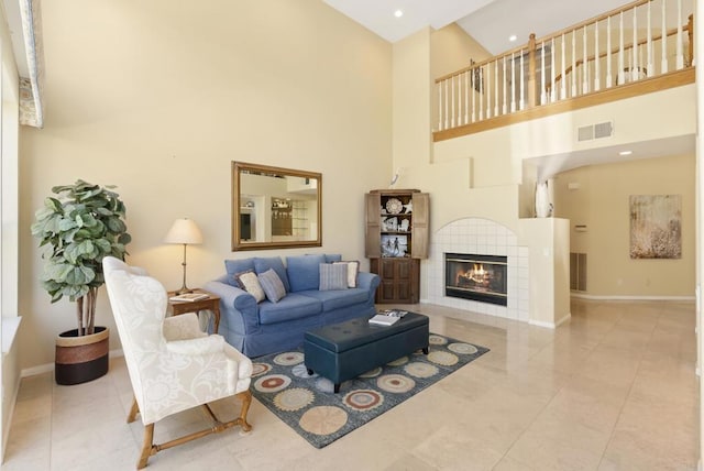 tiled living area with baseboards, a towering ceiling, a tile fireplace, and recessed lighting