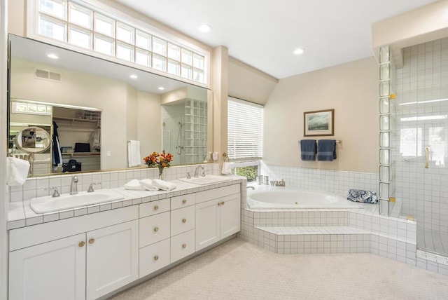 bathroom featuring a shower stall, a bath, double vanity, plenty of natural light, and recessed lighting