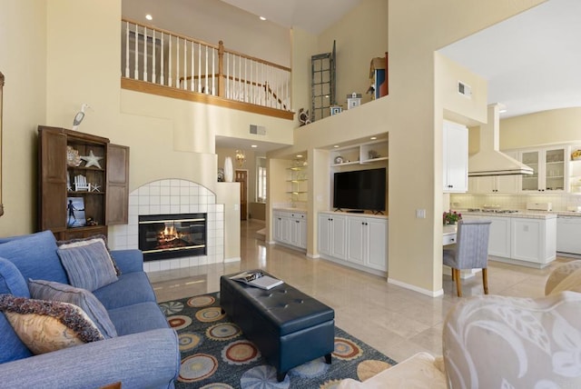 living area with light tile patterned floors, a fireplace, a towering ceiling, and baseboards