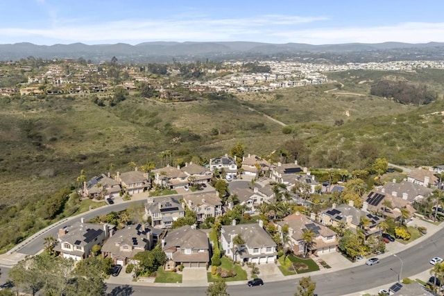 aerial view of property and surrounding area featuring a mountainous background and nearby suburban area