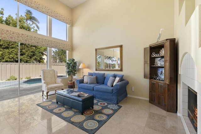 tiled living area with a high ceiling, baseboards, and a tile fireplace