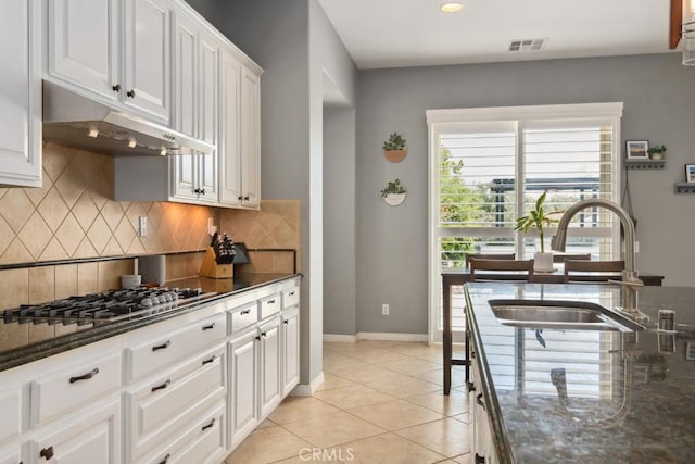 kitchen featuring a sink, under cabinet range hood, visible vents, backsplash, and white cabinetry