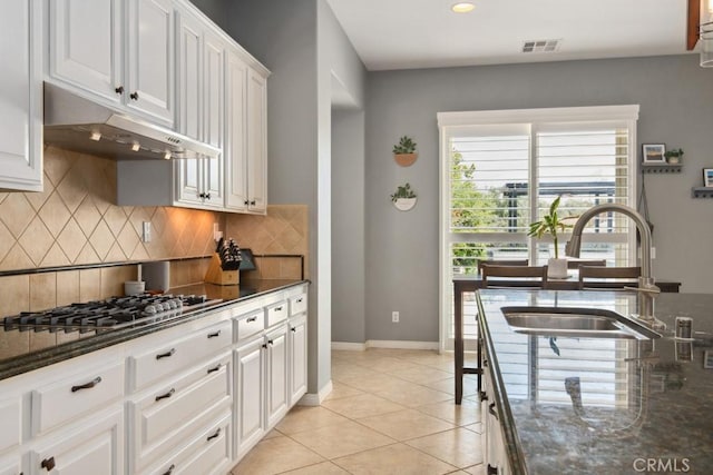 16550 Catalonia Dr, Riverside, CA 92504 - kitchen featuring under cabinet range hood, a sink, decorative backsplash, white cabinets, and dark stone counters