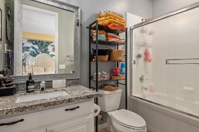 bathroom featuring toilet, shower / bath combination with glass door, and vanity