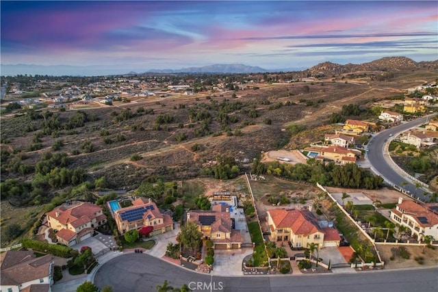 aerial view at dusk featuring a mountain view and a residential view
