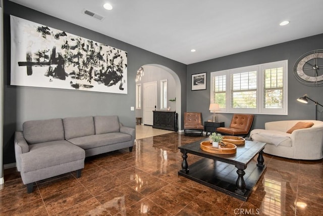 living area with recessed lighting, arched walkways, visible vents, and baseboards