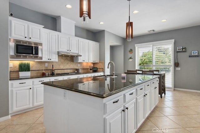 kitchen featuring light tile patterned floors, appliances with stainless steel finishes, under cabinet range hood, and a sink