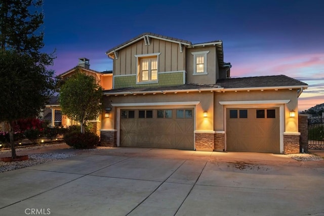 view of front facade featuring driveway, stone siding, an attached garage, and board and batten siding