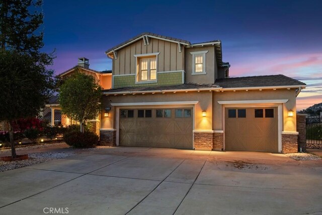 16550 Catalonia Dr, Riverside, CA 92504 - view of front of property featuring a garage, concrete driveway, board and batten siding, stucco siding, and stone siding
