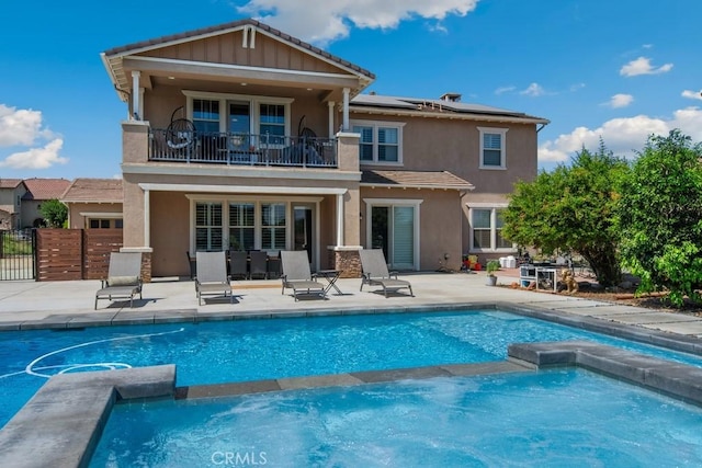 16550 Catalonia Dr, Riverside, CA 92504 - rear view of house with a balcony, a pool with connected hot tub, solar panels, stucco siding, and a patio