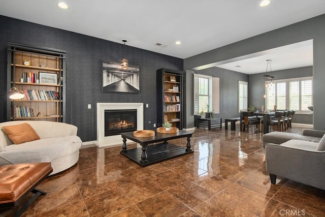 living room with a glass covered fireplace, recessed lighting, and baseboards