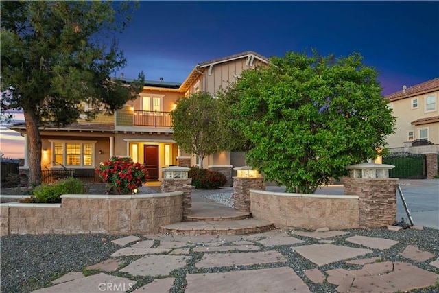 view of front of home featuring a porch, a balcony, stucco siding, and solar panels