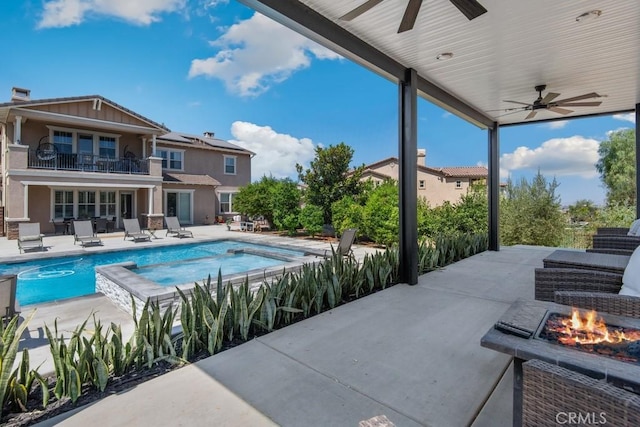 view of pool with a ceiling fan, a fire pit, a pool with connected hot tub, and a patio area