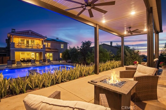 exterior space with ceiling fan, a balcony, an outdoor living space with a fire pit, and an outdoor pool