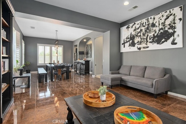 living area with arched walkways, visible vents, and baseboards