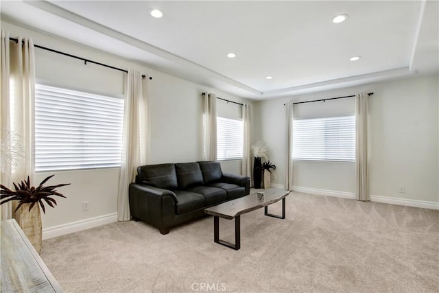 living area featuring baseboards, recessed lighting, a raised ceiling, and light colored carpet