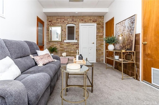living area featuring brick wall, visible vents, a drop ceiling, and carpet