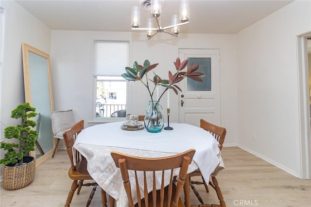 dining room with a chandelier, light wood-style flooring, and baseboards
