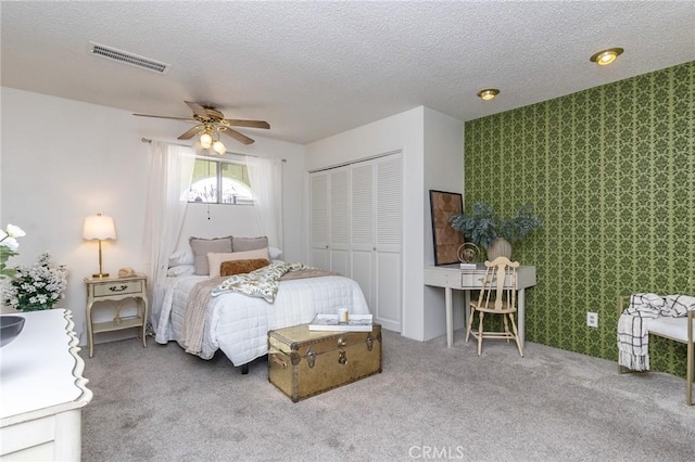 bedroom featuring carpet flooring, visible vents, a closet, and a textured ceiling