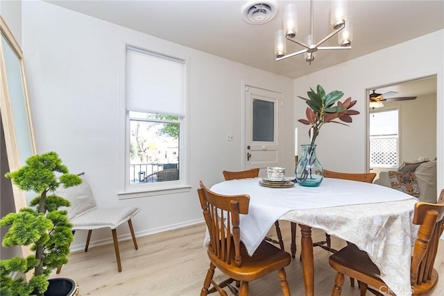 dining room featuring visible vents, baseboards, light wood finished floors, and an inviting chandelier